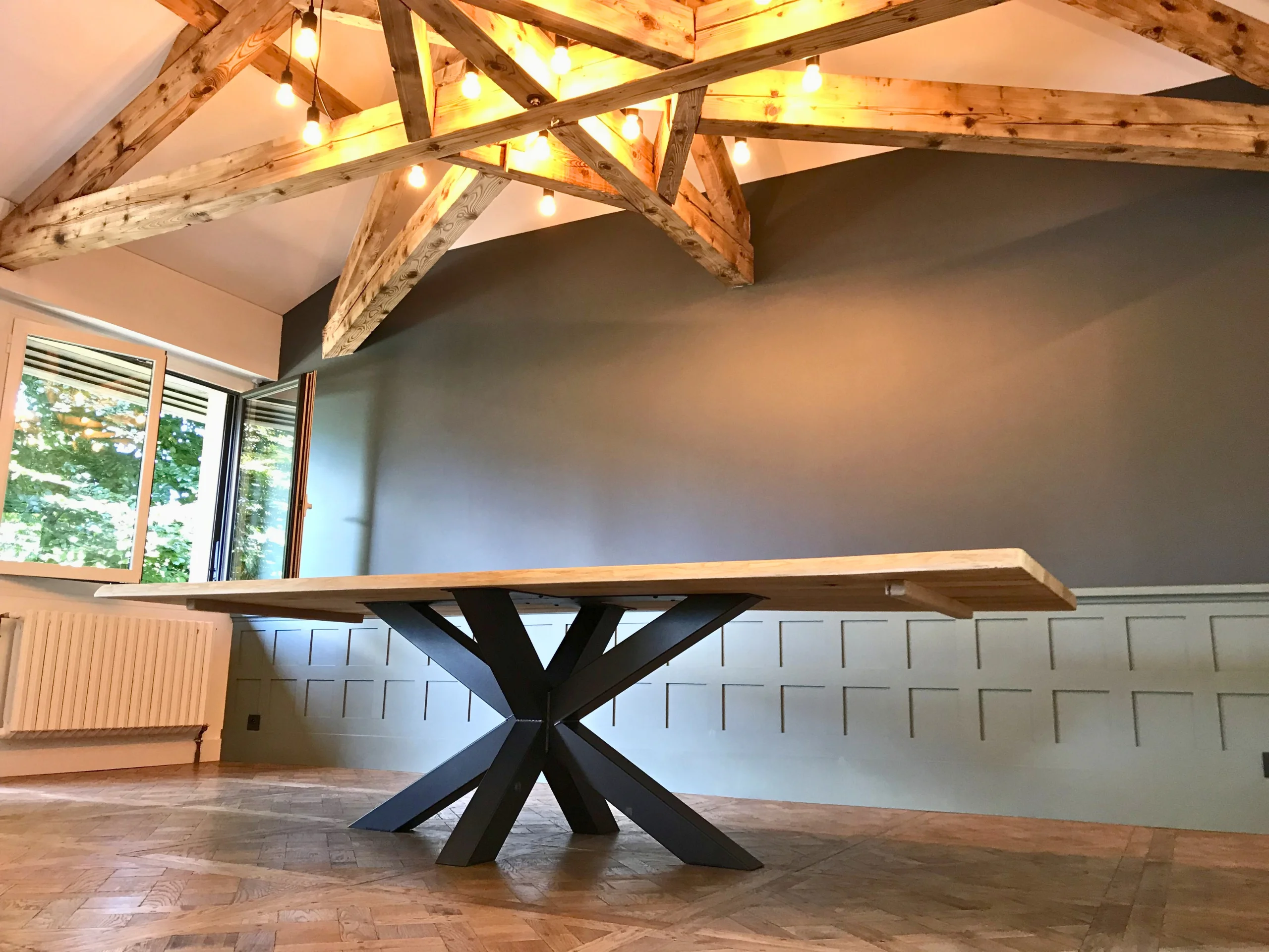 Un grand salon avec un table en bois massif, avec un pied Etoile central acier robuste